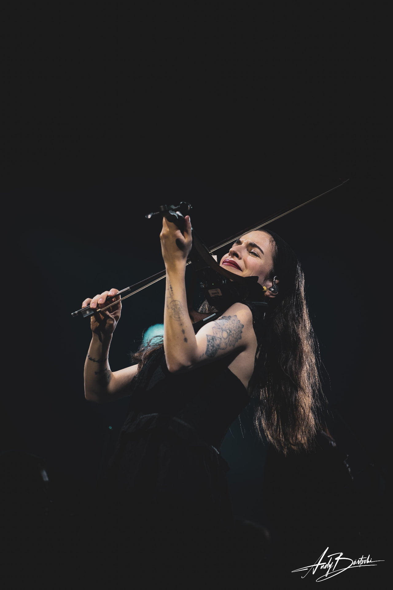 Berfin Aksu playing violin under a single stage light