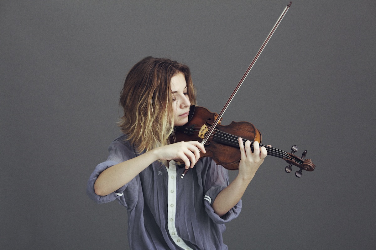 Berfin Aksu playing the violin, photographed against a plain grey backdrop